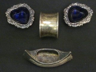 A Victorian silver pin cushion in the form of a boat marked  Abbeville, Birmingham 1899, a waisted silver napkin ring and a  pair of silver plated heart shaped salts with blue glass liners