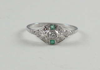 A lady's 18ct white gold dress ring set an emerald surrounded by diamonds