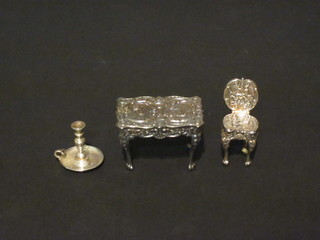A miniature silver chamber stick marked Sterling, and a modern embossed miniature silver table and do. chair