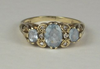 A lady's gold dress ring set 3 blue stones supported by diamonds