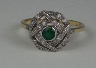 A lady's 18ct yellow gold dress ring set a circular cut emerald supported by numerous diamonds