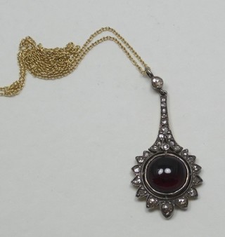 A cabouchon cut garnet pendant surrounded by diamonds hung  on a fine gold chain