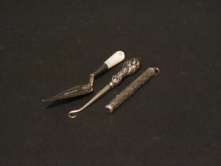 A silver bladed bookmark in the form of a trowel, a silver cased toothpick and a silver handled button hook