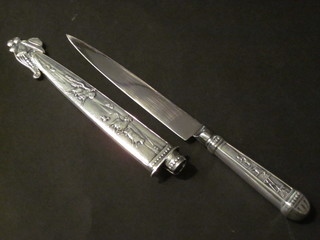 A paper knife with silver plated handle and scabbard decorated cowboy scenes