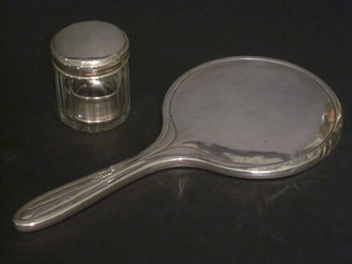 A silver backed hand mirror, a silver napkin ring and a panel cut glass dressing table jar with silver lid