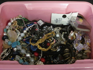 A pink crate containing a collection of costume jewellery