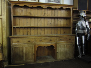A large pine dresser with moulded cornice, the back fitted 2 shelves, the base fitted 3 drawers above a recess flanked by a  pair of cupboards 94"