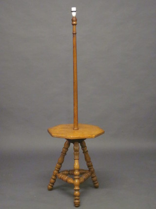 A turned oak standard lamp the base incorporating an octagonal  wine table, raised on turned supports