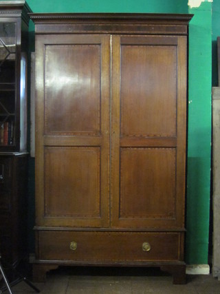 A 19th Century inlaid mahogany wardrobe with moulded and  dentil cornice, enclosed by panelled doors, the base fitted a  drawer, raised on bracket feet, 51"