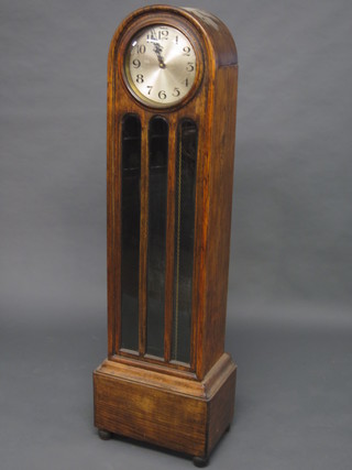 A 1930's Grandmother clock with 10" circular dial with Arabic numerals, contained in an oak arched case,