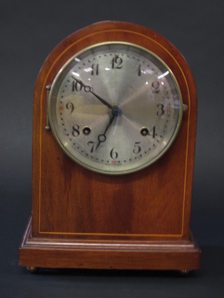 An Edwardian American bracket clock with silvered dial and Arabic numerals contained in an arch shaped inlaid mahogany  case