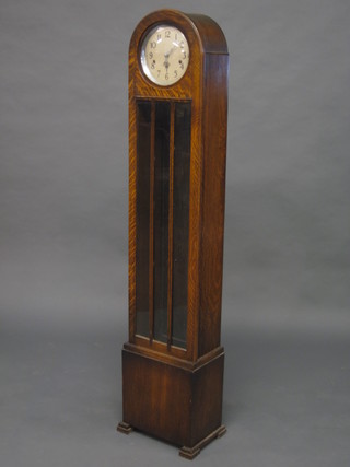 An Art Deco 8 day chiming Granddaughter clock with silvered dial and Arabic numerals contained in an oak arch shaped case on  bracket feet, no weights, 61"