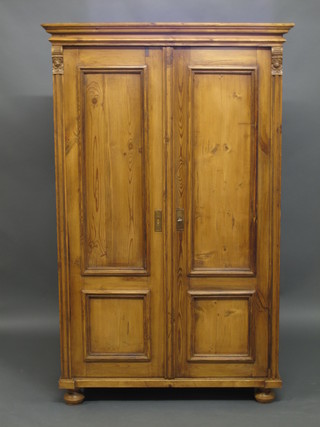 A pine cupboard with moulded cornice, fitted shelves enclosed by panelled doors 42", raised on bun feet