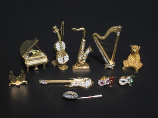 5 Swarovski gilt metal figures of instruments - grand piano,  violin and bow, harp electric guitar and saxophone together with  a gilt model of a seated bear, 2 gilt and jewelled pins and a  Swarovski pin