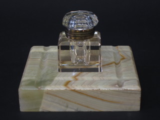A square cut glass inkwell, raised on an onyx base 6"