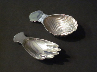 A modern silver scallop shaped caddy spoon and 1 other in the  form of a hand