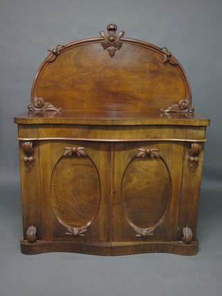 A Victorian mahogany chiffonier of serpentine outline and with  raised back, the base fitted cupboards enclosed by panelled doors  48"