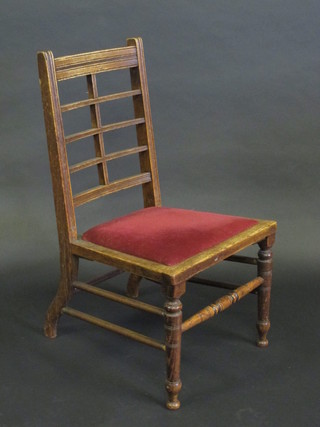 A Victorian oak nursing chair with fretwork back, raised on  turned supports