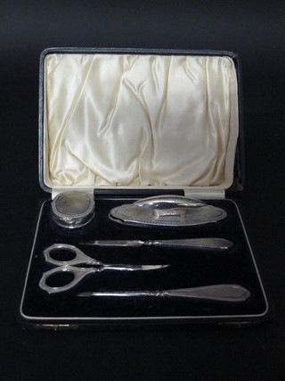 A silver 5 piece manicure set comprising nail buffer, circular rouge pot with silver lid, f, nail file, pair of scissors and 1 other  implement, Birmingham 1925, cased