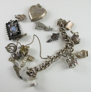 A silver curb link charm bracelet hung numerous charms, a silver  heart shaped locket and various other charms