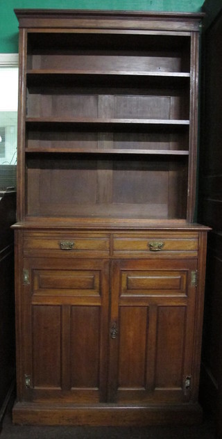 An Edwardian walnut bookcase on cabinet the upper section with moulded cornice fitted adjustable shelves, the base fitted 2 long  drawers above a double cupboard enclosed by panelled doors,  raised on a platform base 37"
