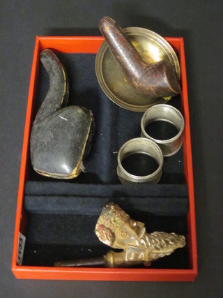 A pipe in the form of an Alsatian, do. Turk, 1 other pipe, a small metal dish, 2 Oriental waisted napkin rings