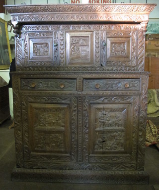 A 19th Century heavily carved oak court cupboard, the upper section enclosed by panelled doors, the base fitted 2 drawers  above a double cupboard, 59"
