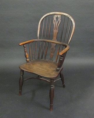 An elm comb back Windsor armchair with solid seat and cow  horn stretcher, raised on turned supports