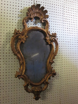 A shaped plate mirror contained in a carved gilt wood frame 20"