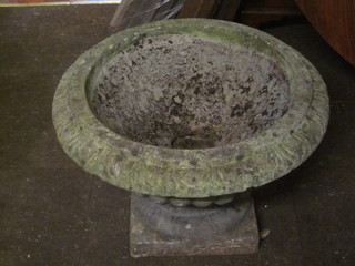 A pair of circular stoneware garden urns, raised on square bases 23"