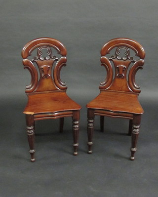 A pair of Victorian mahogany hall chairs with solid seats, raised on turned supports
