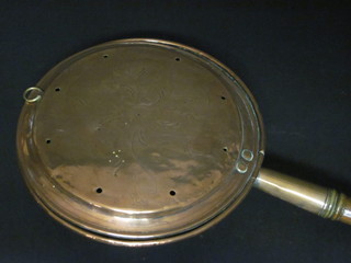 A copper warming pan with turned handle