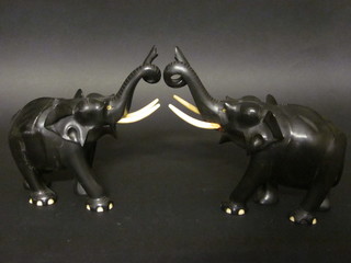 A pair of carved ebony figures of walking elephants with ivory tusks