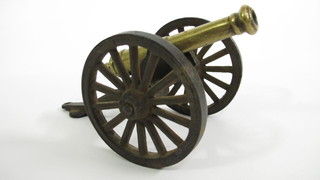 A model of a cannon with 5" brass barrel raised on an iron  carriage