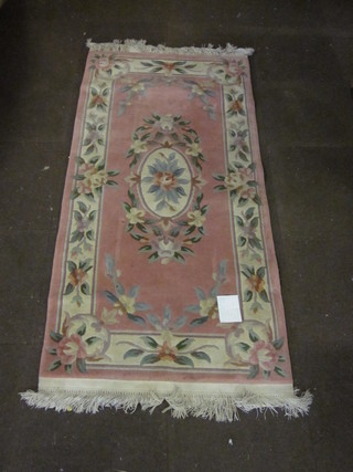 A pink ground and floral patterned Chinese rug 75" x 37"