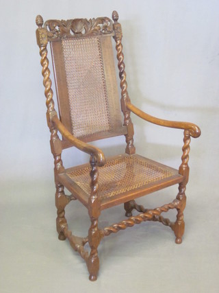 A Victorian carved oak Carolean style open arm carver chair  with woven cane seat and back, raised on spiral turned supports  with H framed stretcher