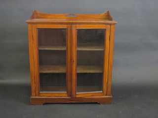 An Edwardian Art Nouveau walnut bookcase with raised  three-quarter gallery, fitted shelves enclosed by glazed panelled  doors, raised on a platform base 35"