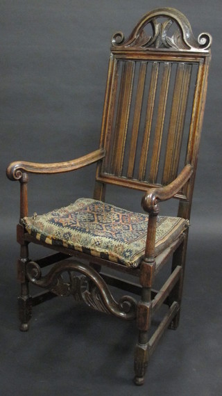 A 17th/18th Century oak stick and rail back open arm chair with  solid seat, raised on turned and block supports, with old repair to  legs,