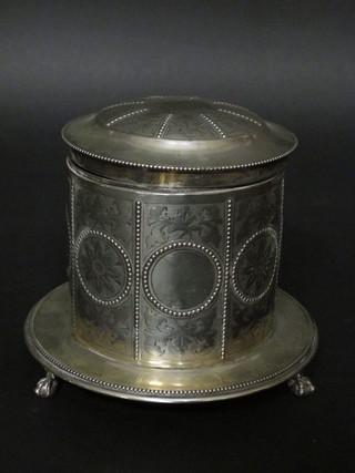 A silver plated engraved cylindrical biscuit barrel with hinged lid raised on 3 claw supports