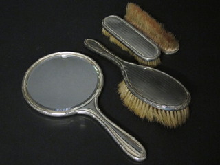 A silver backed 4 piece dressing table set comprising hand  mirror, pair of clothes brushes and a hair brush