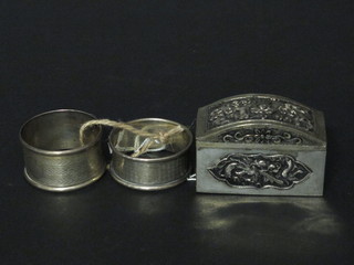 A pair of silver napkin rings with engraved decoration and an Eastern embossed white metal arch shaped trinket box with  hinged lid 2 1/2"