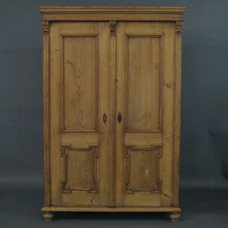A Continental stripped and polished pine cupboard with moulded cornice, the shelved interior enclosed by panelled doors 45"