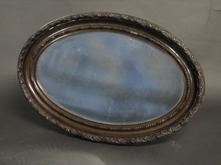 An oval bevelled plate wall mirror contained in a carved frame  32"