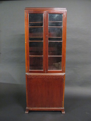 An Art Deco mahogany display cabinet, the upper section fitted adjustable shelves enclosed by glazed panelled doors, the base  fitted a cupboard enclosed by panelled door raised on bracket feet  23"