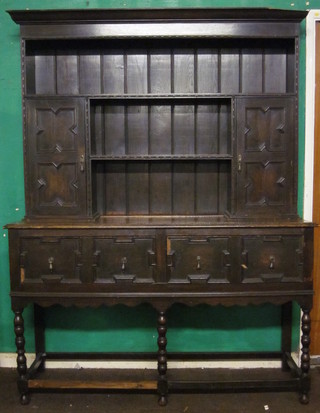 A Jacobean style oak dresser, the raised back fitted 3 shelves flanked by a pair of cupboards, the base fitted 2 long drawers,  raised on spiral turned supports 59"