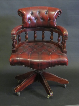 A mahogany revolving office chair upholstered in red buttoned  leather