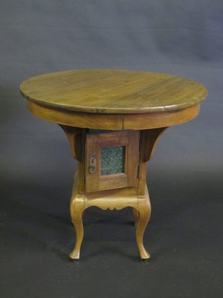 An Art Nouveau circular Eastern hardwood occasional table, the base fitted a cupboard enclosed by a glazed panelled door, raised  on cabriole supports 27"