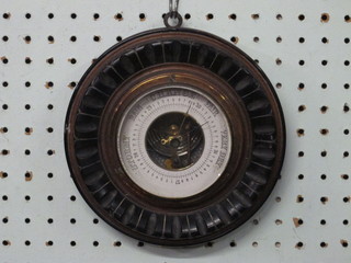 A circular aneroid barometer with paper dial contained in a carved walnut case 7"