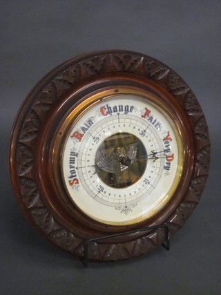 An Edwardian aneroid barometer with porcelain dial contained in  a circular carved walnut case 13"