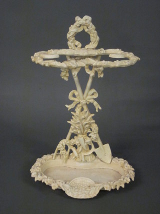 A Victorian style white painted cast iron umbrella stand with gardening trophies